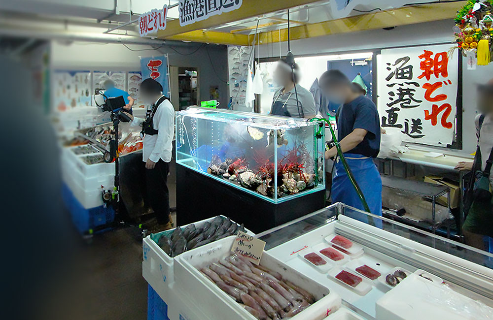 朝どれ漁港直送の看板と鮮魚店内の大型活魚水槽