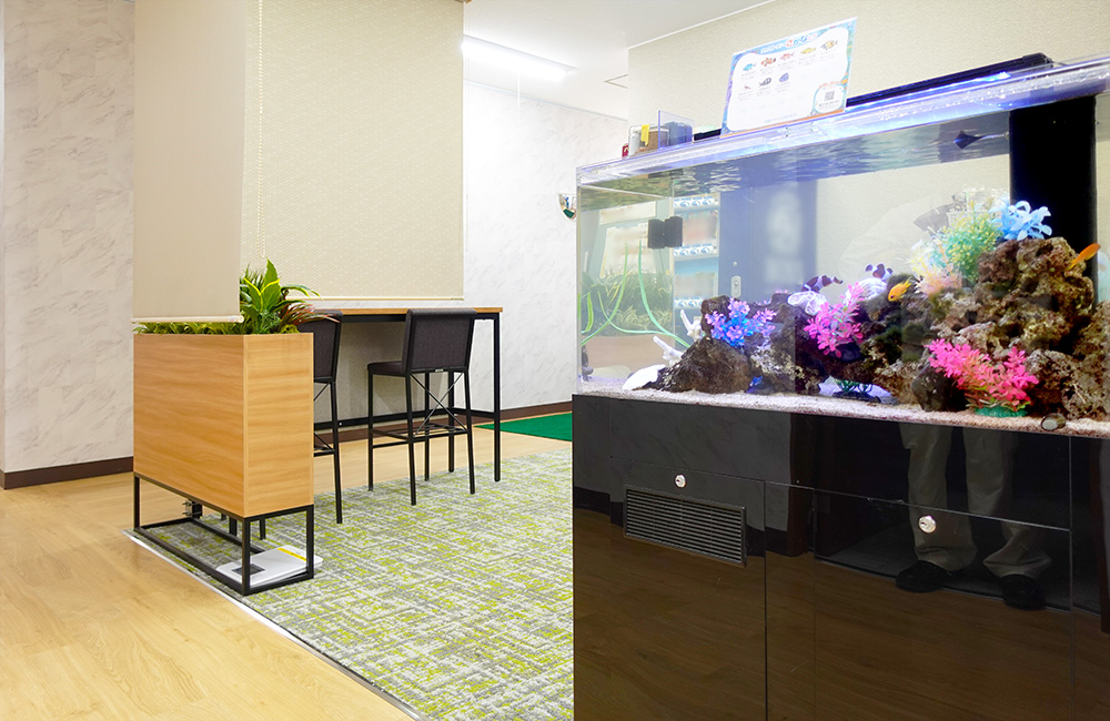 カラフルな人工水草を配置したオフィス内の大型水槽