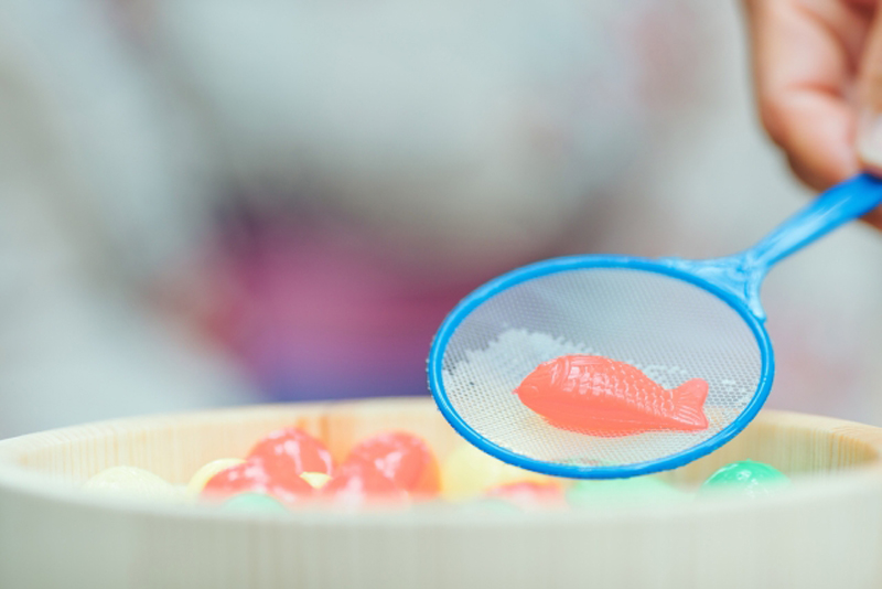 青いポイで掬い上げられた赤い金魚のおもちゃ