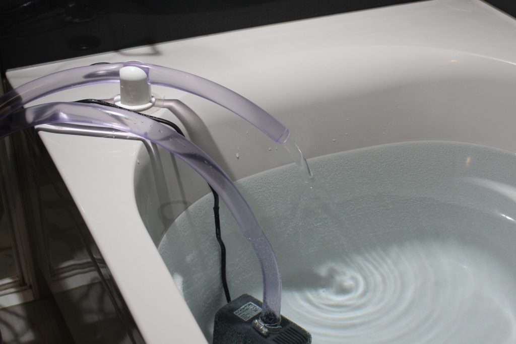 水中ポンプとホースで浴槽に注水する様子