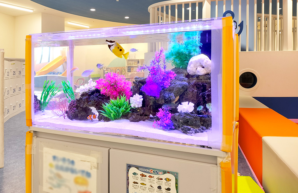 カラフルな人工水草と海水魚が泳ぐキッズルームの水槽