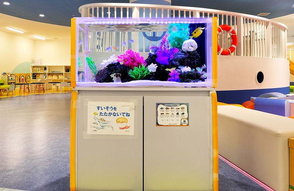 カラフルな人工サンゴと海水魚が泳ぐキッズスペースの水槽