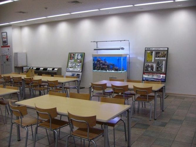 休憩スペースに設置された大型の海水魚水槽とテーブル席