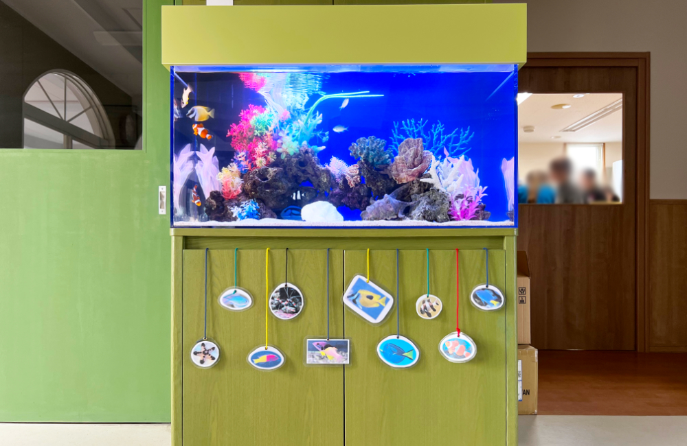 魚の写真が飾られた緑の水槽台と海水魚水槽の全景