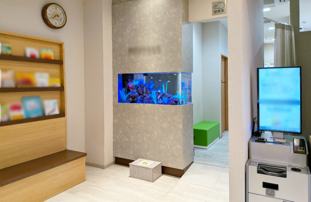 クリニック待合室の壁に埋め込まれた青い照明の水槽
