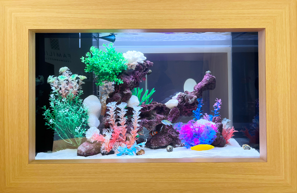木目調フレームに囲まれたカラフルな人工水草の海水魚水槽